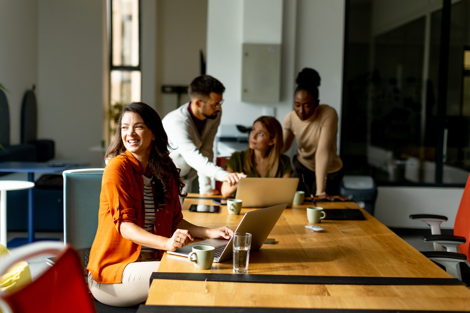 Diverse team of business professionals collaborating around a laptop in a modern office